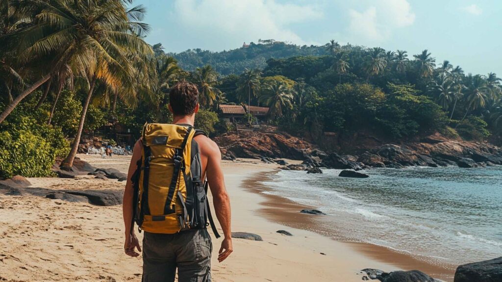 A traveler with a backpack walks along a scenic beach in Goa, India, with palm trees, golden sand, and a vibrant sunset in the background